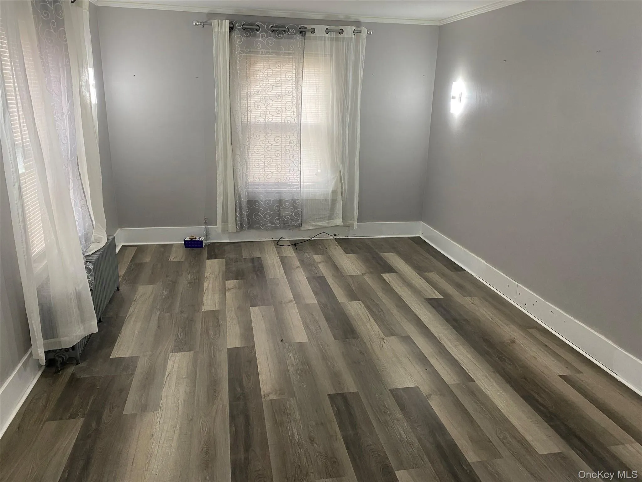 Unfurnished room with ornamental molding and dark wood-type flooring Unfurnished room with ornamental molding and dark wood-type flooring