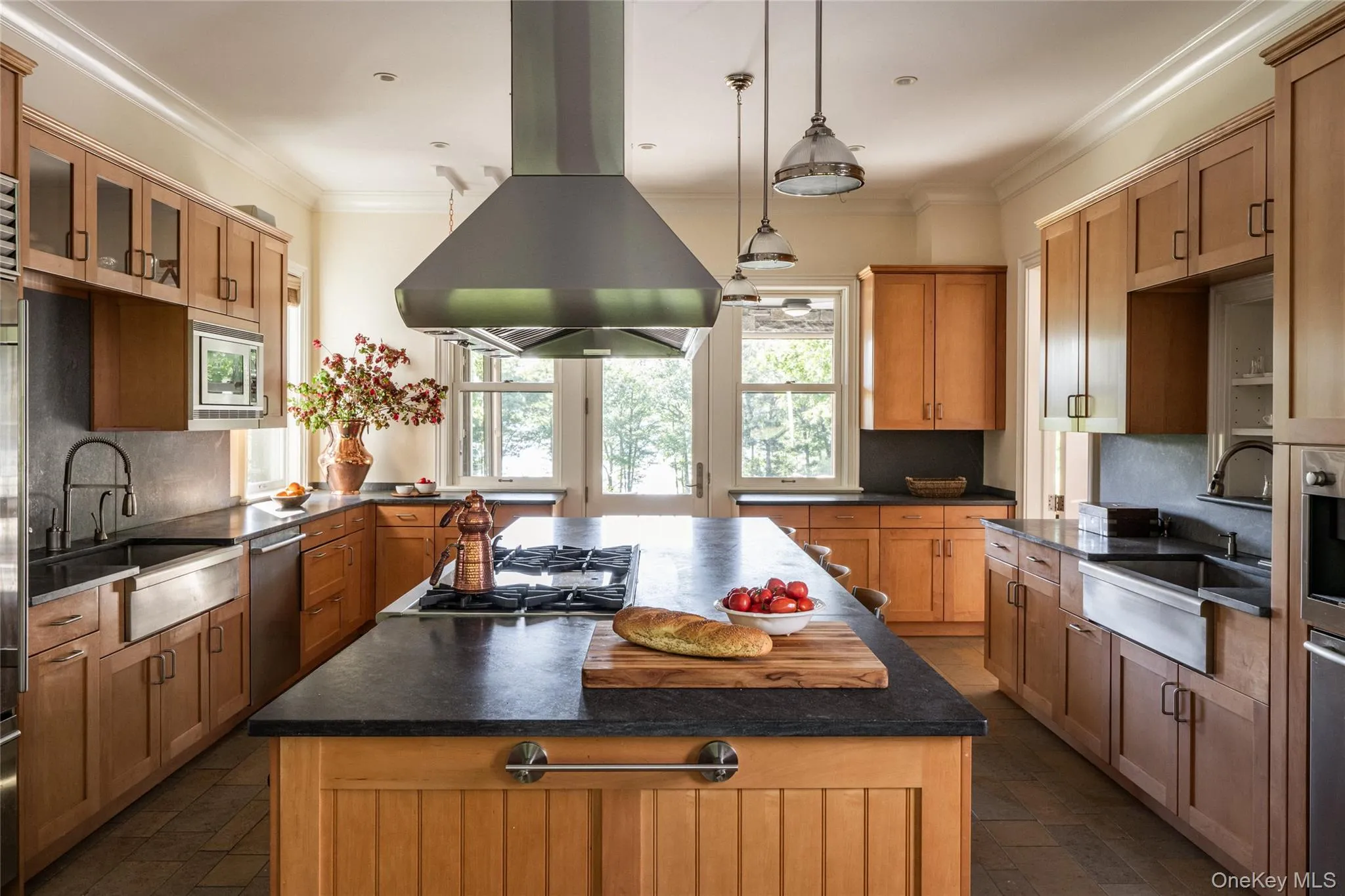 Kitchen featuring decorative backsplash, island exhaust hood, brown cabinetry, a kitchen island, and ornamental molding Kitchen featuring decorative backsplash, island exhaust hood, brown cabinetry, a kitchen island, and ornamental molding