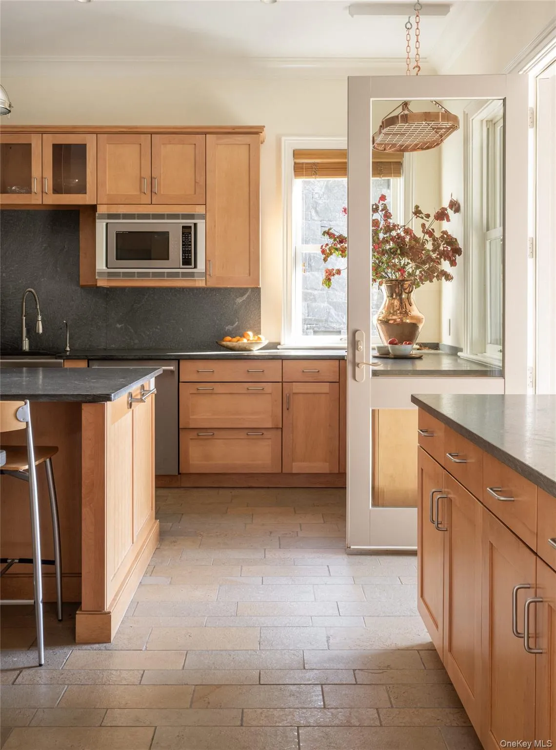 Kitchen featuring backsplash, a kitchen breakfast bar, stainless steel appliances, dark stone countertops, and ornamental molding Kitchen featuring backsplash, a kitchen breakfast bar, stainless steel appliances, dark stone countertops, and ornamental molding