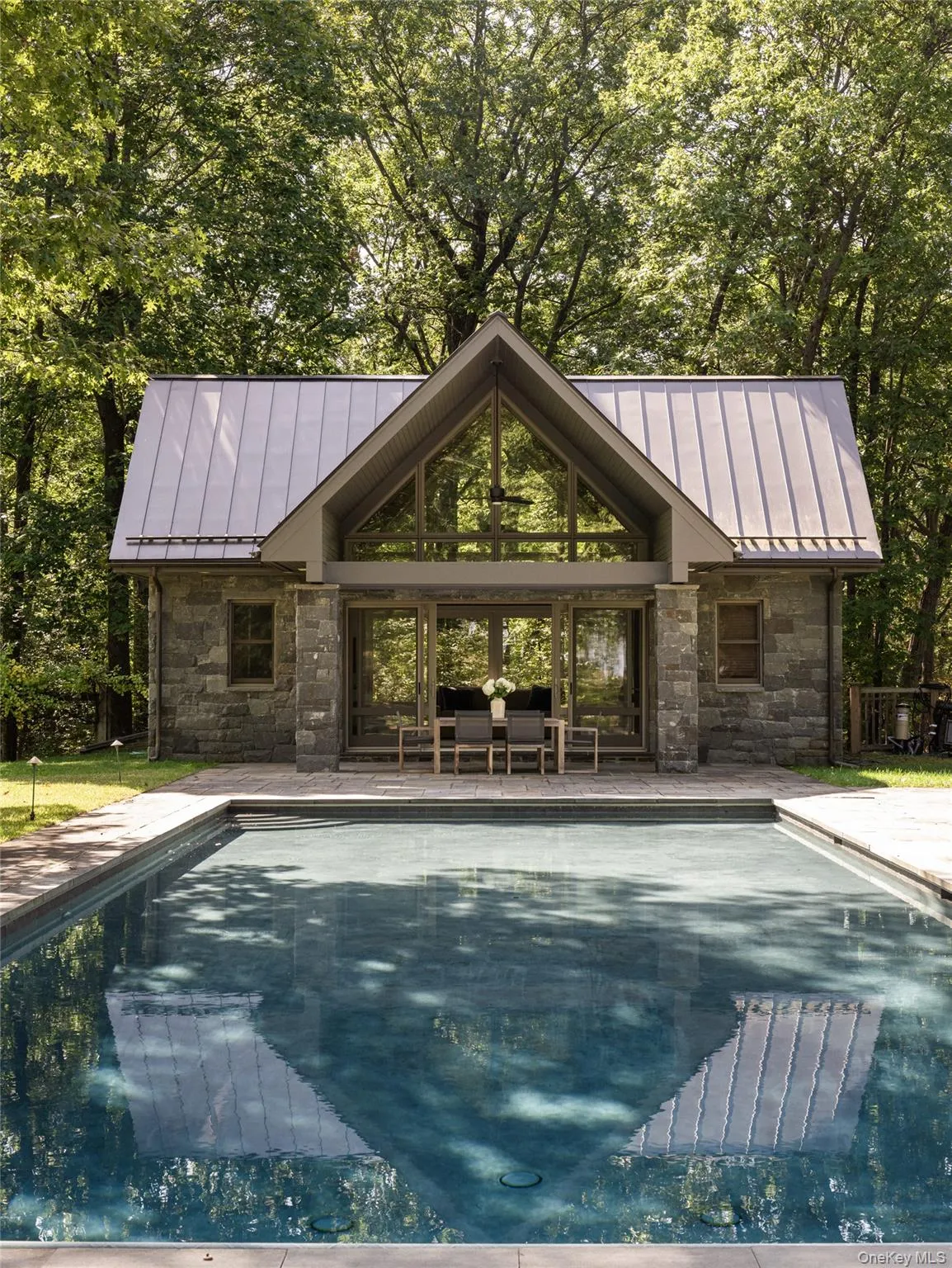 Swimming pool featuring an exterior structure, an outdoor structure, a patio, and view of scattered trees Swimming pool featuring an exterior structure, an outdoor structure, a patio, and view of scattered trees