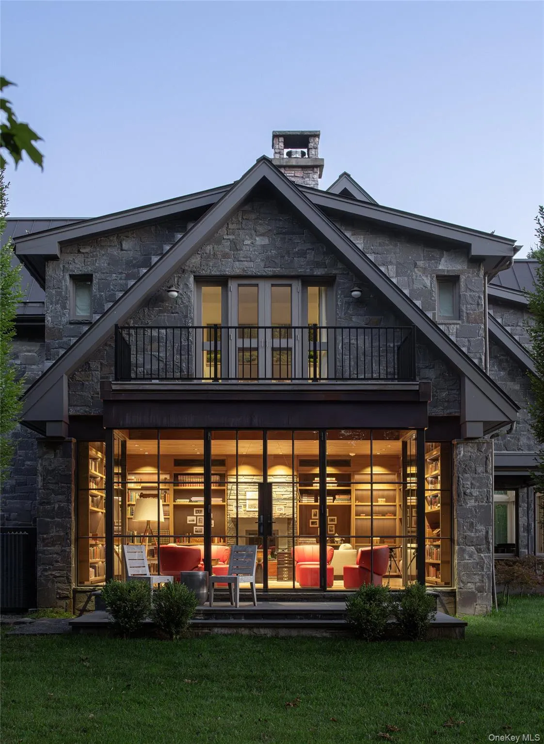 Back of house featuring stone siding, a balcony, and a yard Back of house featuring stone siding, a balcony, and a yard