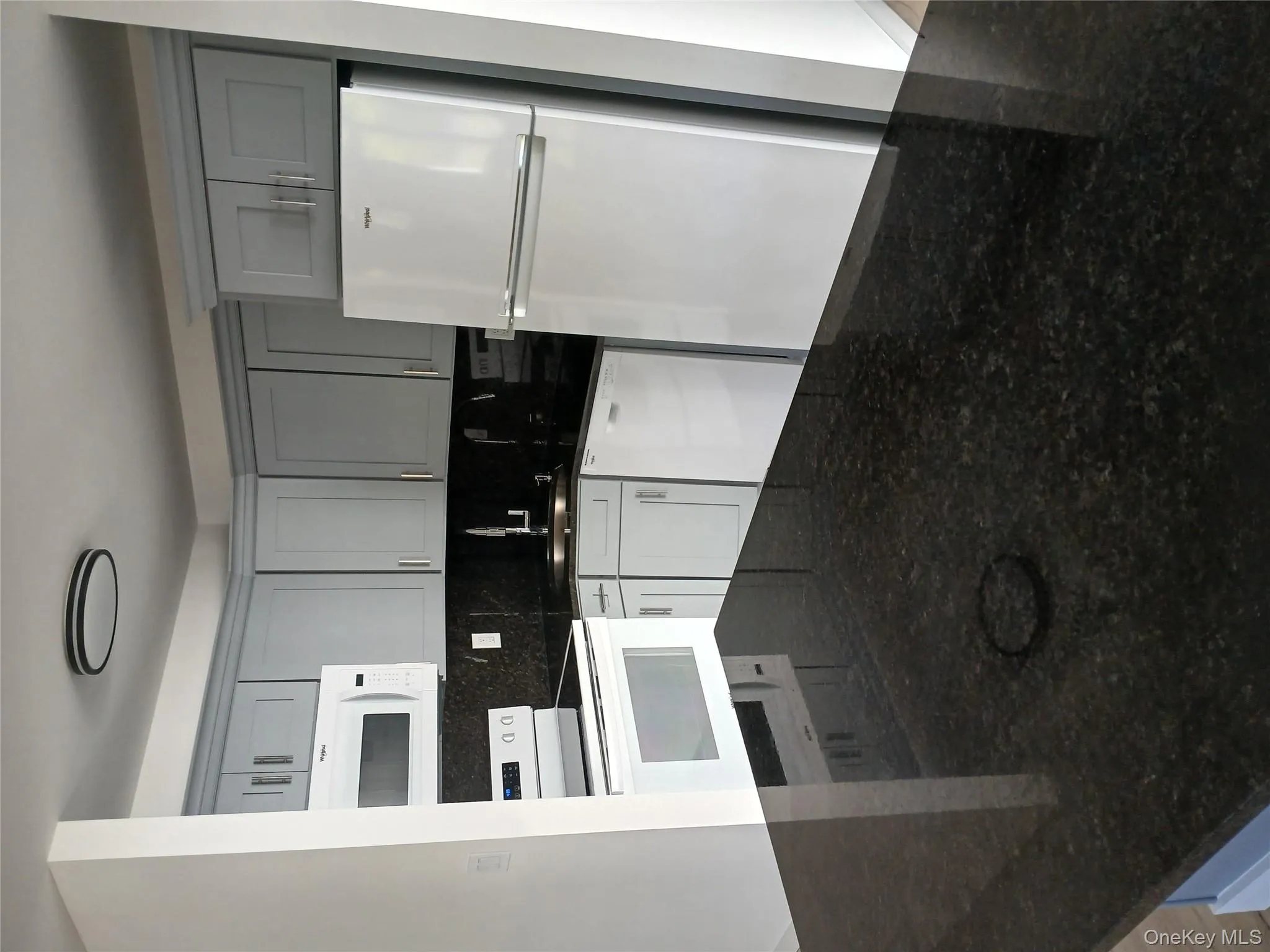 Kitchen featuring dark stone countertops, black refrigerator, range, and white microwave Kitchen featuring dark stone countertops, black refrigerator, range, and white microwave