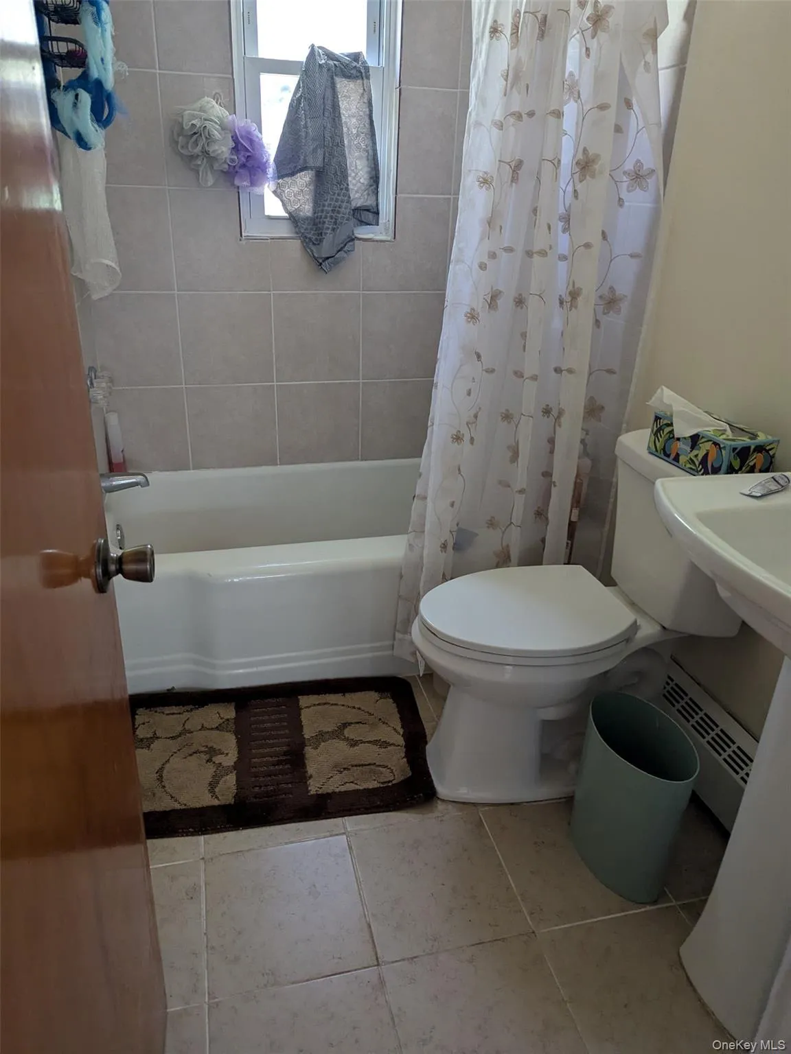 Full bath featuring a baseboard radiator, shower / bath combination with curtain, and light tile patterned floors Full bath featuring a baseboard radiator, shower / bath combination with curtain, and light tile patterned floors