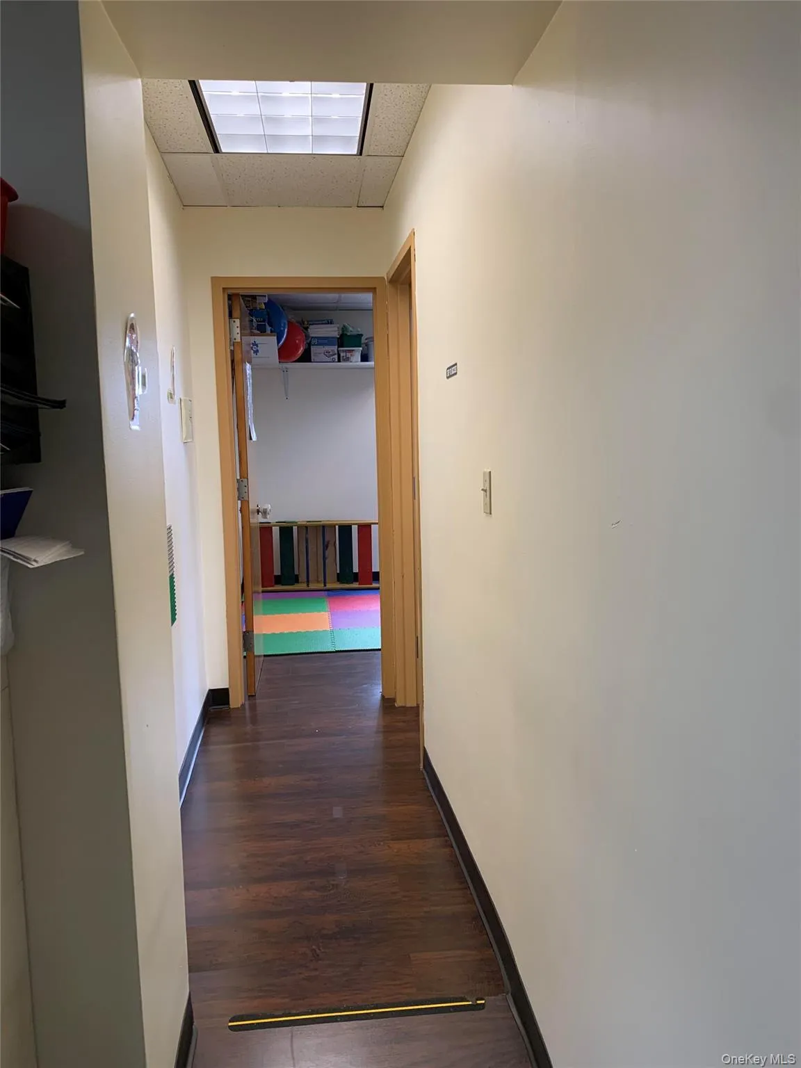Hallway featuring a drop ceiling and dark wood finished floors Hallway featuring a drop ceiling and dark wood finished floors