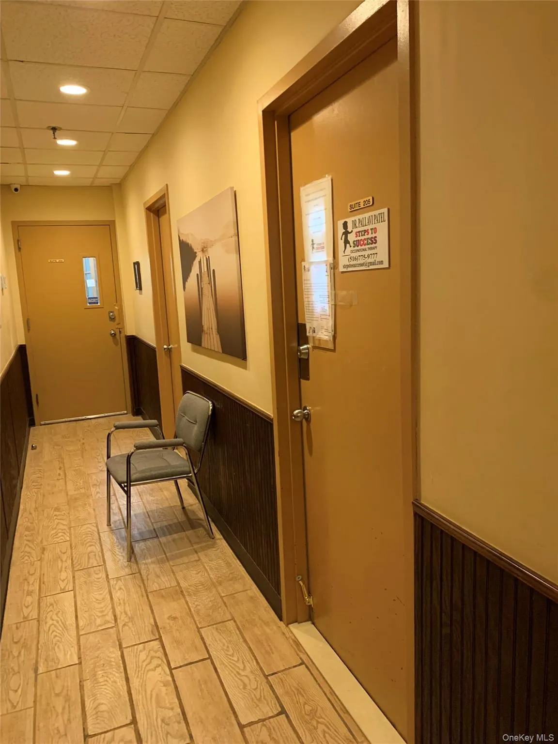 Corridor featuring wainscoting, a paneled ceiling, wood walls, light wood-type flooring, and recessed lighting Corridor featuring wainscoting, a paneled ceiling, wood walls, light wood-type flooring, and recessed lighting