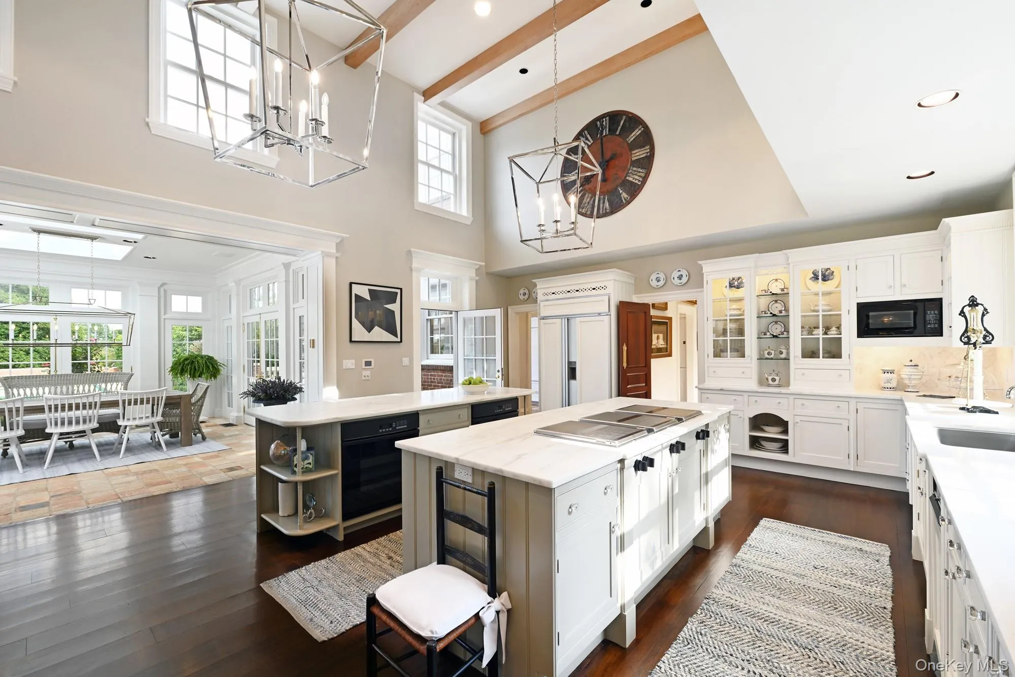 Kitchen featuring white cabinetry, open shelves, light stone counters, glass insert cabinets, and a high ceiling Kitchen featuring white cabinetry, open shelves, light stone counters, glass insert cabinets, and a high ceiling