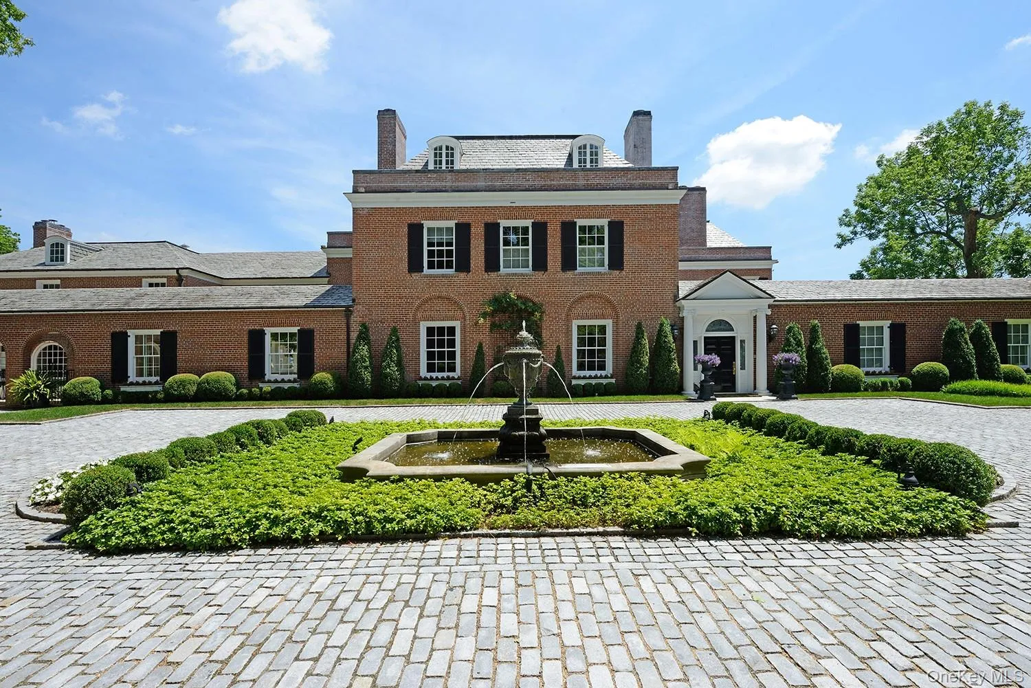 Colonial inspired home featuring brick siding, a chimney, curved driveway, and a high end roof Colonial inspired home featuring brick siding, a chimney, curved driveway, and a high end roof