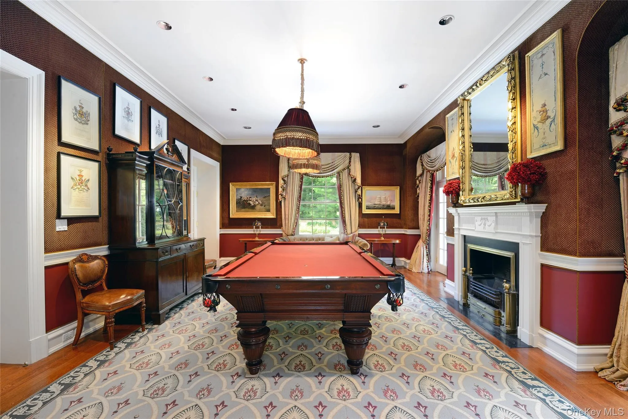 Rec room featuring a wainscoted wall, wood finished floors, ornamental molding, pool table, and a fireplace with flush hearth Rec room featuring a wainscoted wall, wood finished floors, ornamental molding, pool table, and a fireplace with flush hearth