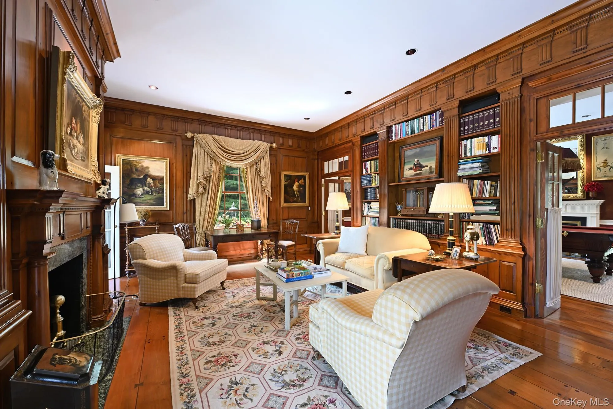 Living area with a high end fireplace, wooden walls, wood-type flooring, and ornamental molding Living area with a high end fireplace, wooden walls, wood-type flooring, and ornamental molding