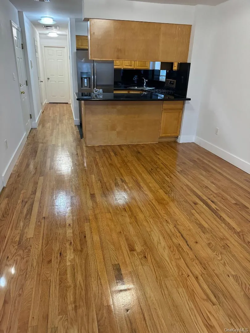 Kitchen with light wood-style floors, brown cabinets, a peninsula, and appliances with stainless steel finishes Kitchen with light wood-style floors, brown cabinets, a peninsula, and appliances with stainless steel finishes