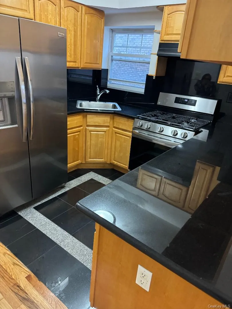 Kitchen with appliances with stainless steel finishes, under cabinet range hood, and brown cabinets Kitchen with appliances with stainless steel finishes, under cabinet range hood, and brown cabinets