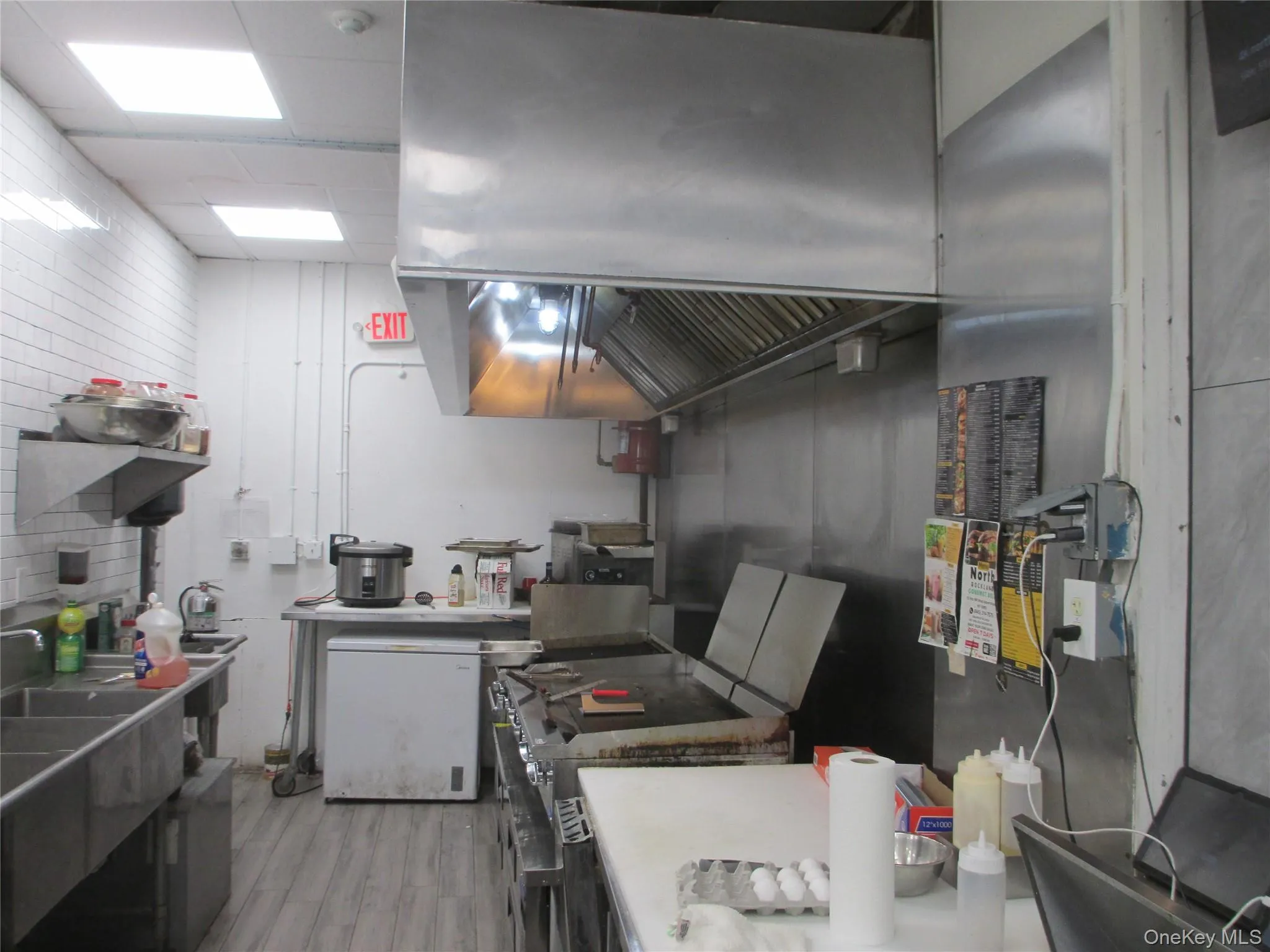 Kitchen with island exhaust hood, light wood-style flooring, range, and light countertops Kitchen with island exhaust hood, light wood-style flooring, range, and light countertops