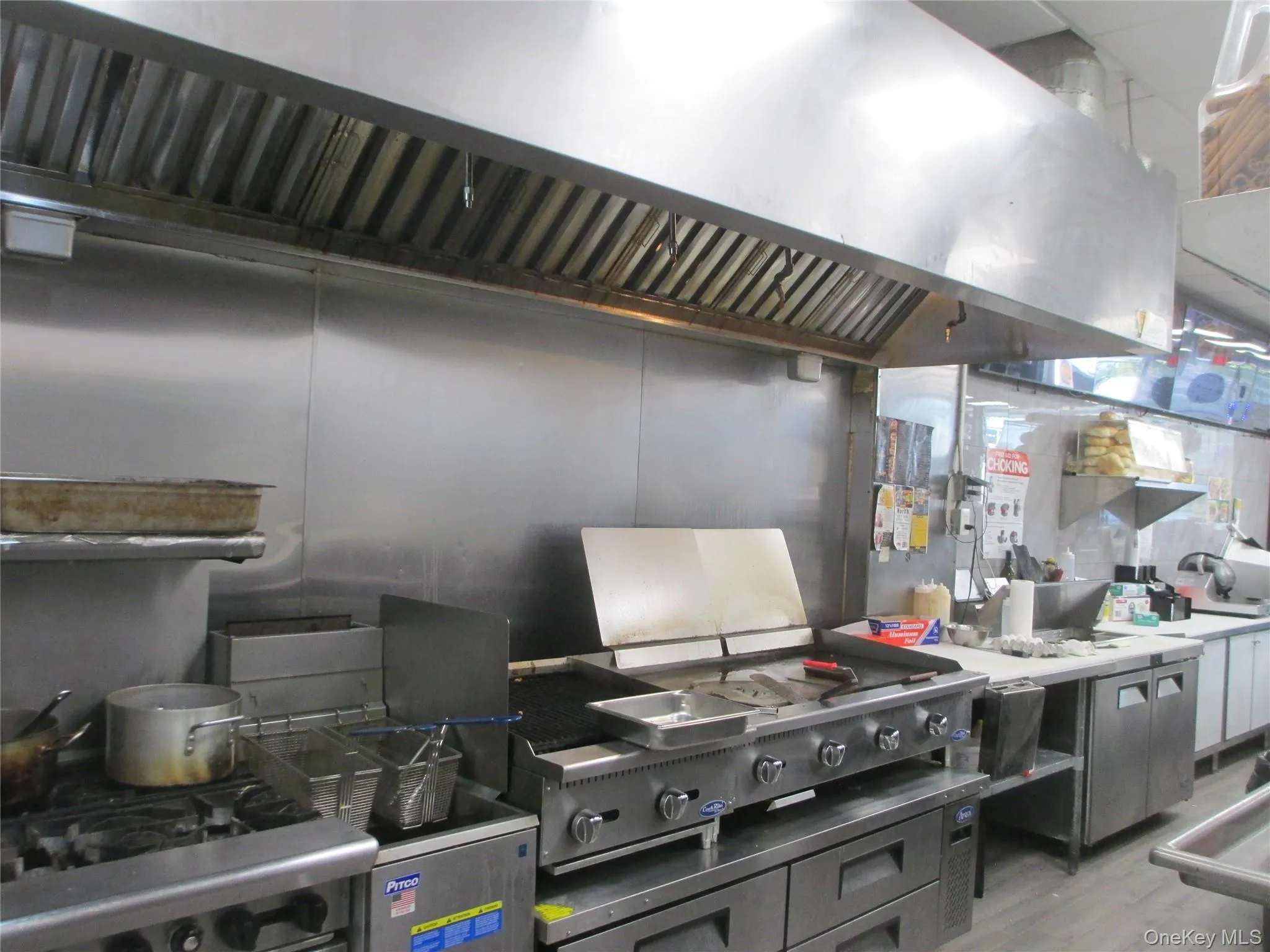 Kitchen featuring exhaust hood, gas stove, light wood-type flooring, and light countertops Kitchen featuring exhaust hood, gas stove, light wood-type flooring, and light countertops