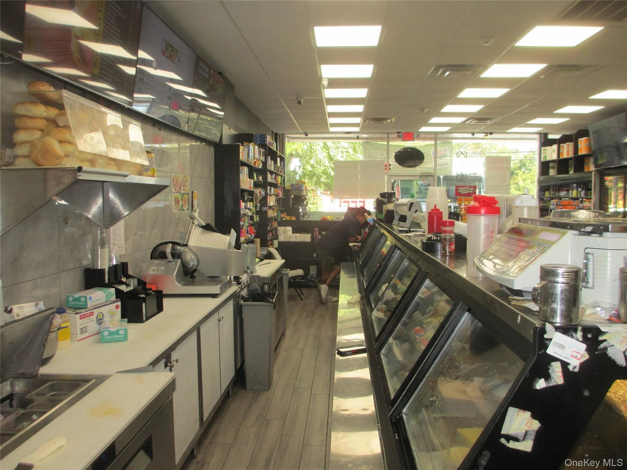 Kitchen featuring open shelves, healthy amount of natural light, white cabinets, a drop ceiling, and light wood finished floors Kitchen featuring open shelves, healthy amount of natural light, white cabinets, a drop ceiling, and light wood finished floors