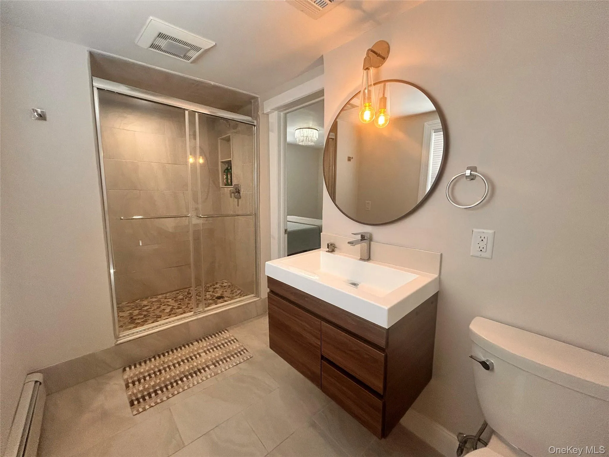 Bathroom with a stall shower, vanity, light tile patterned flooring, and a baseboard radiator Bathroom with a stall shower, vanity, light tile patterned flooring, and a baseboard radiator
