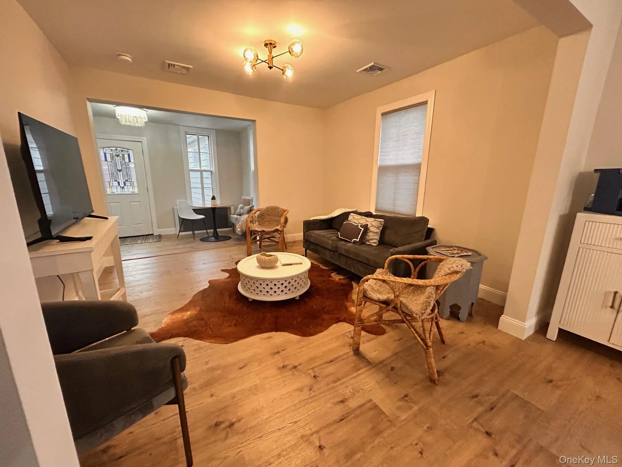 Living room featuring light wood-type flooring and a chandelier Living room featuring light wood-type flooring and a chandelier