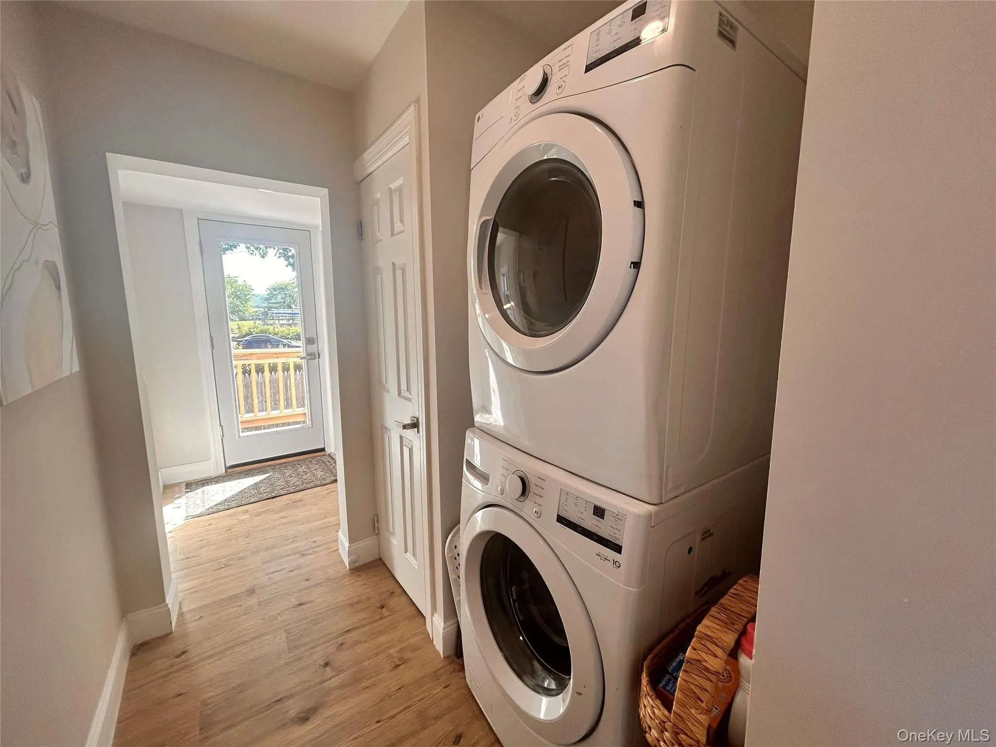 Laundry room with light wood-style flooring and stacked washer / drying machine Laundry room with light wood-style flooring and stacked washer / drying machine