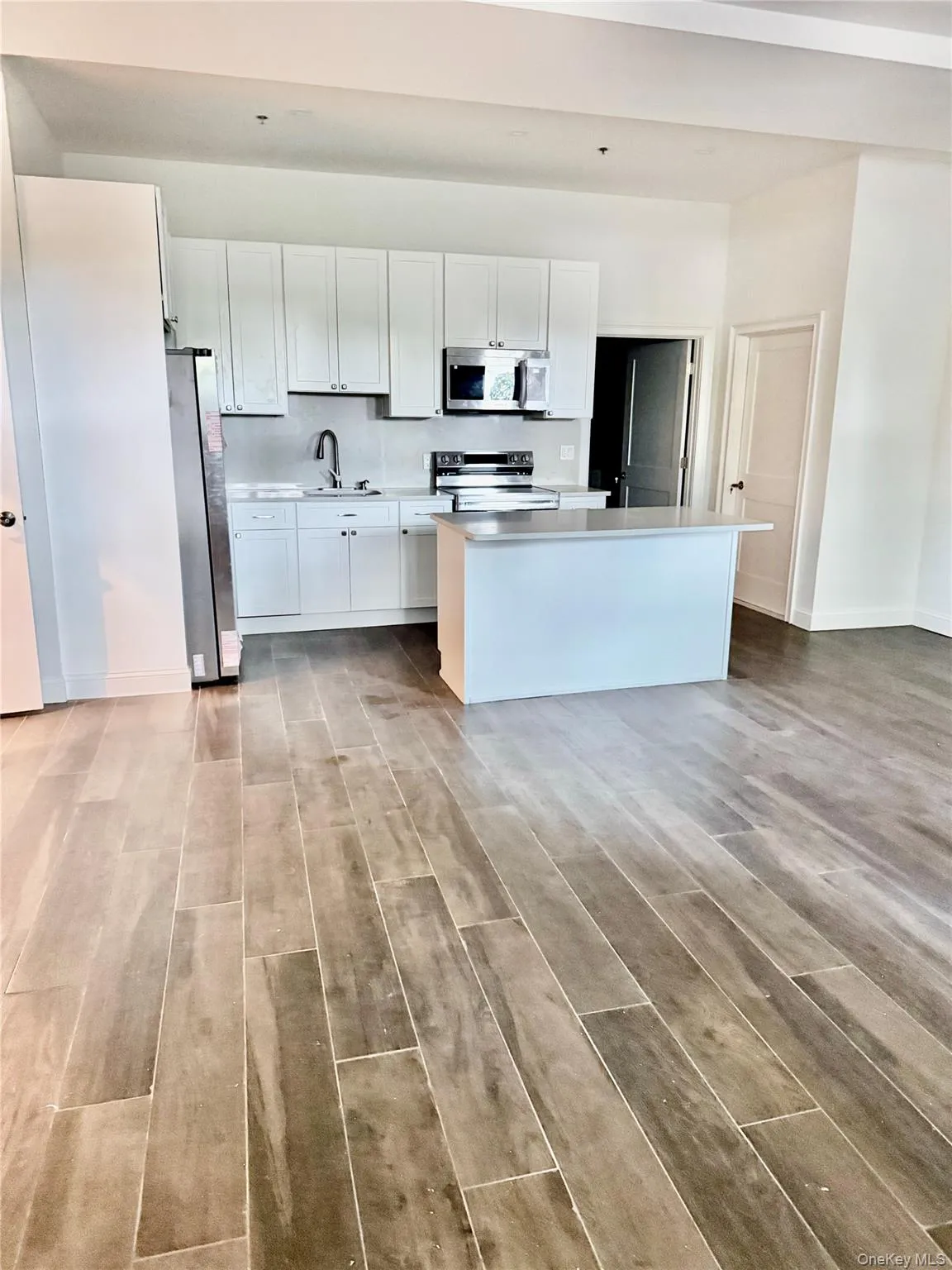 Kitchen with white cabinets, light wood-type flooring, light countertops, and stainless steel appliances Kitchen with white cabinets, light wood-type flooring, light countertops, and stainless steel appliances