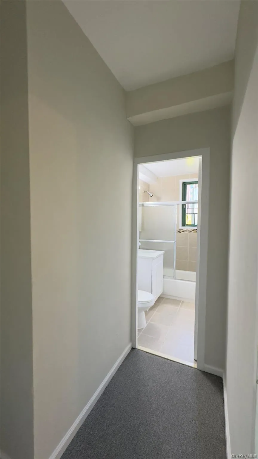 Hallway featuring baseboards and light colored carpet Hallway featuring baseboards and light colored carpet
