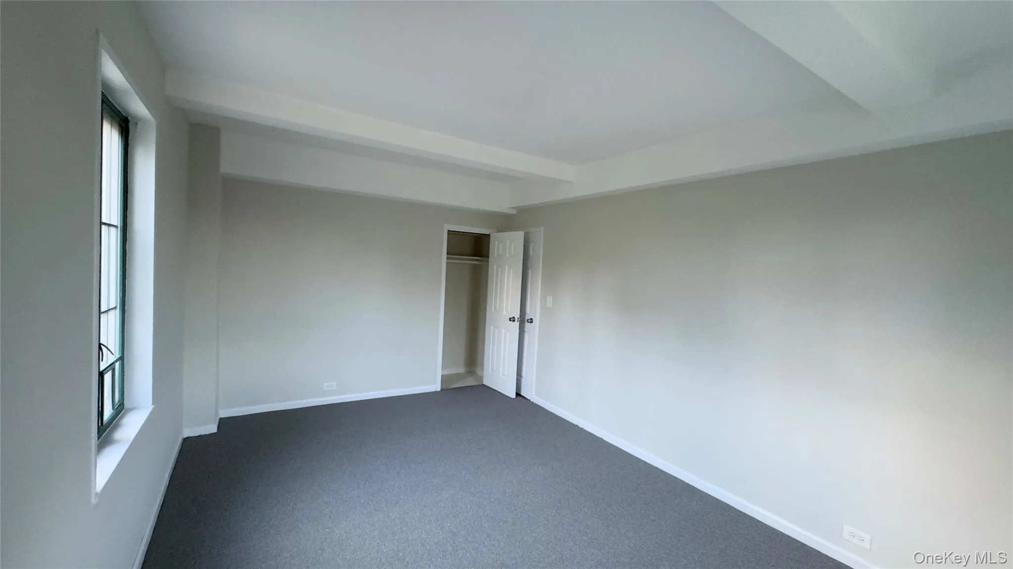 Unfurnished bedroom with beamed ceiling, a closet, and carpet floors Unfurnished bedroom with beamed ceiling, a closet, and carpet floors