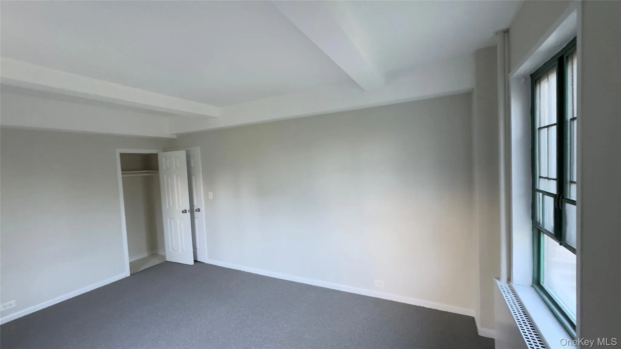 Unfurnished bedroom with beamed ceiling, a closet, and carpet flooring Unfurnished bedroom with beamed ceiling, a closet, and carpet flooring