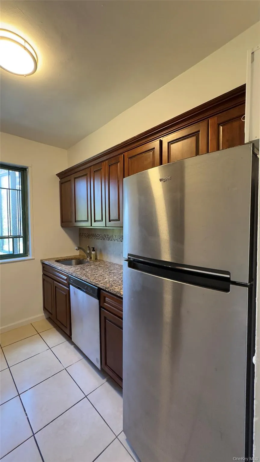 Kitchen with stainless steel appliances, dark stone counters, and light tile patterned floors Kitchen with stainless steel appliances, dark stone counters, and light tile patterned floors