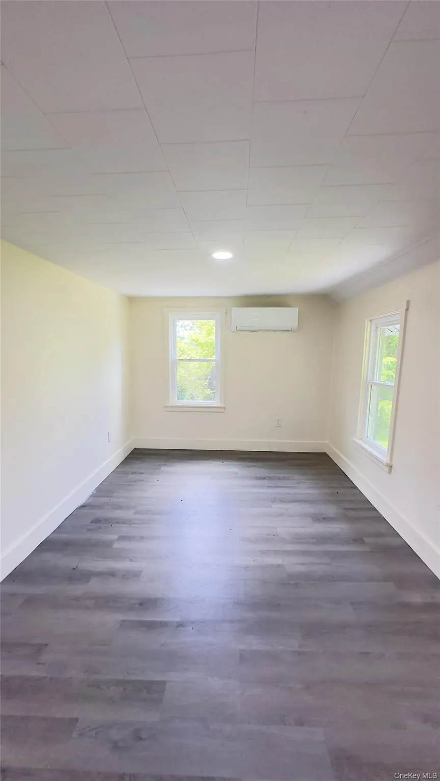 Unfurnished room with a wall mounted air conditioner, healthy amount of natural light, vinyl floors, and recessed lighting Unfurnished room with a wall mounted air conditioner, healthy amount of natural light, vinyl floors, and recessed lighting