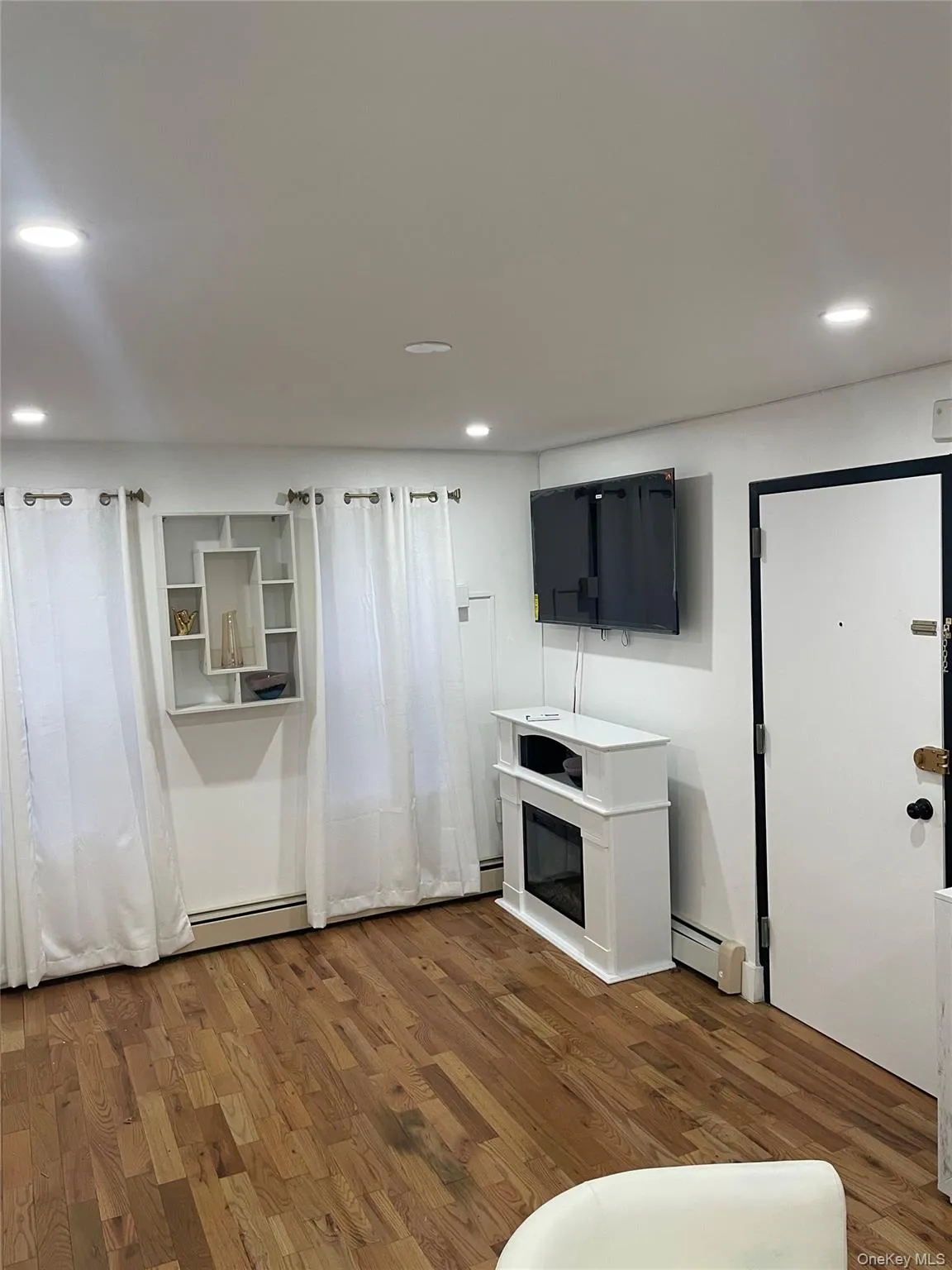 Kitchen with dark wood-type flooring, a baseboard radiator, light countertops, and recessed lighting Kitchen with dark wood-type flooring, a baseboard radiator, light countertops, and recessed lighting