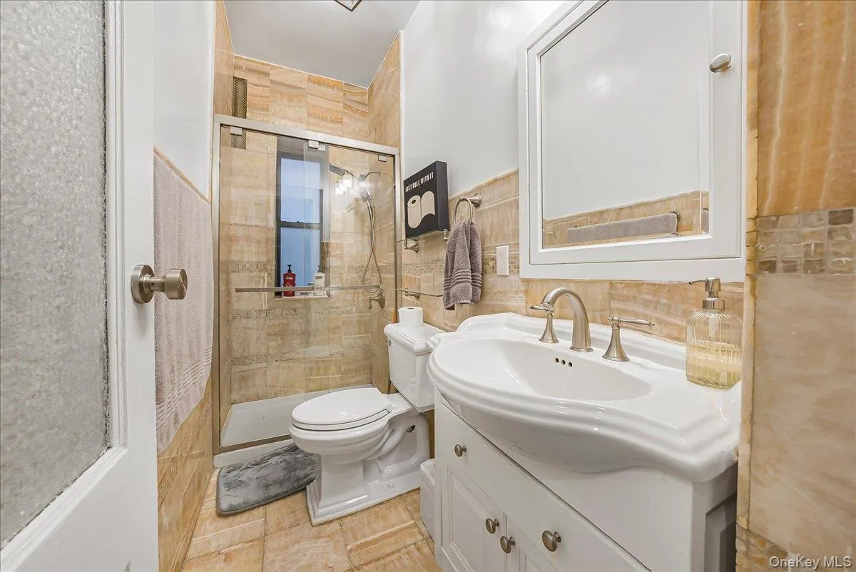 Bathroom featuring vanity, a shower stall, and tile walls Bathroom featuring vanity, a shower stall, and tile walls