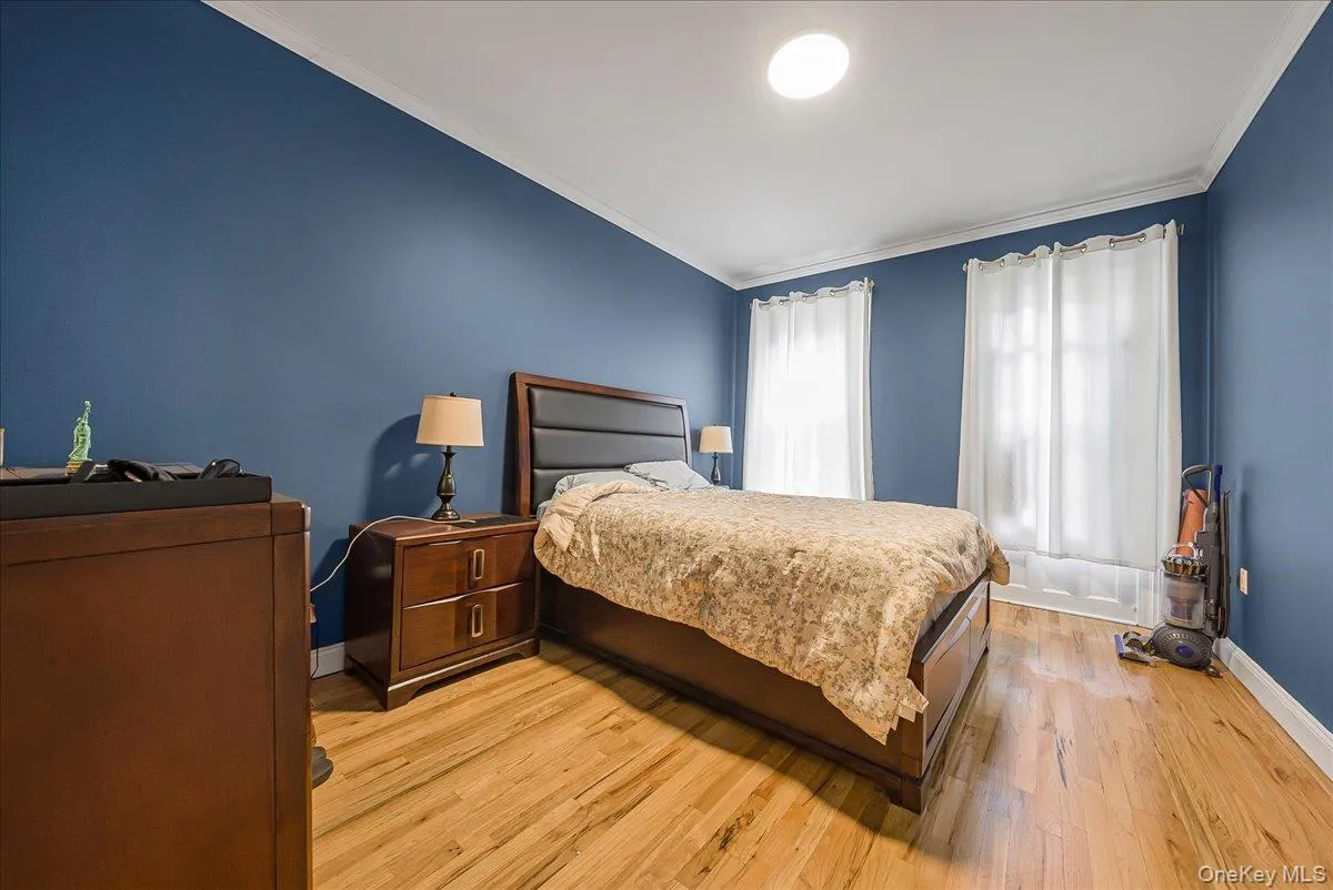 Bedroom featuring crown molding and light wood finished floors Bedroom featuring crown molding and light wood finished floors