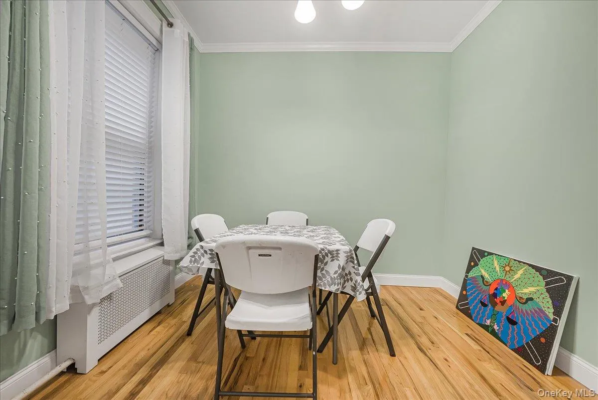 Dining area featuring radiator heating unit, light wood-style flooring, and ornamental molding Dining area featuring radiator heating unit, light wood-style flooring, and ornamental molding