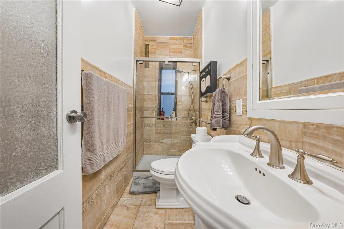 Bathroom featuring a stall shower, tile walls, and light tile patterned floors Bathroom featuring a stall shower, tile walls, and light tile patterned floors