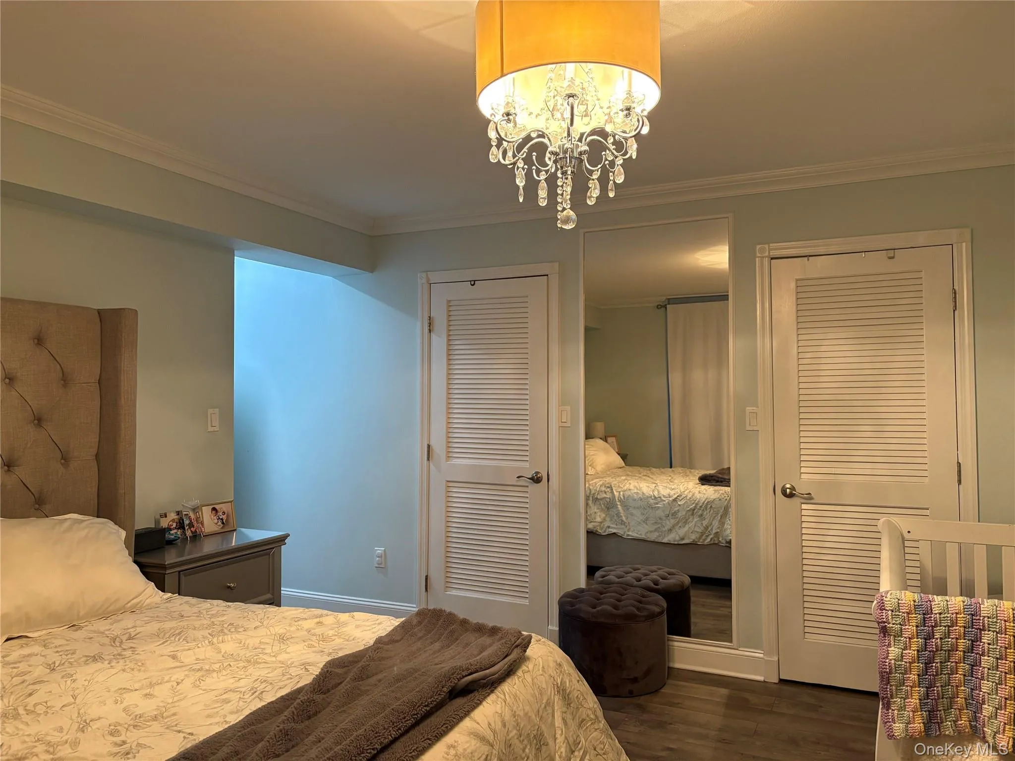 Bedroom with multiple closets, crown molding, dark wood-type flooring, and a chandelier Bedroom with multiple closets, crown molding, dark wood-type flooring, and a chandelier