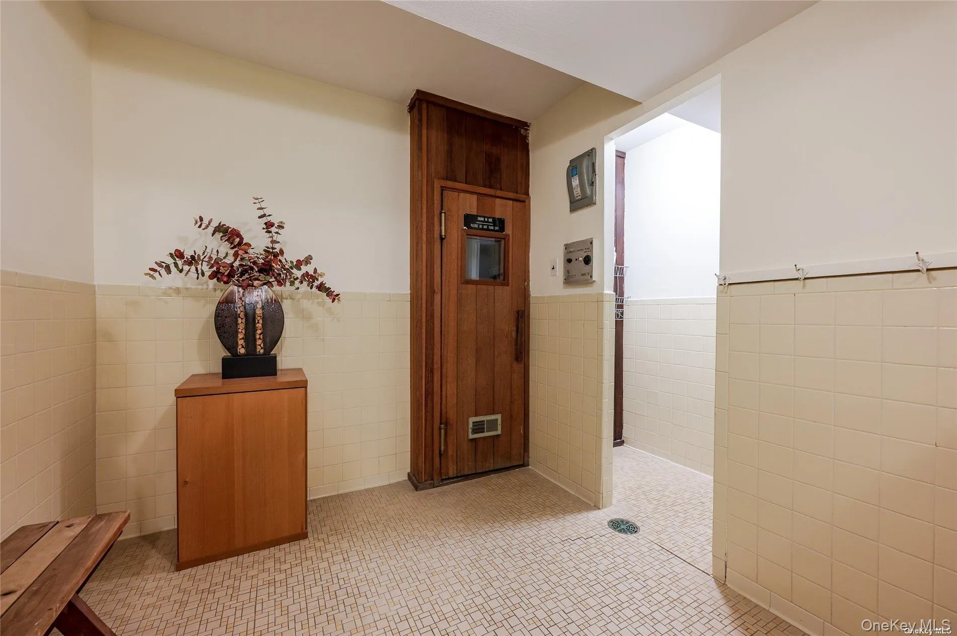 Hall featuring wainscoting, tile walls, and light tile patterned floors Hall featuring wainscoting, tile walls, and light tile patterned floors