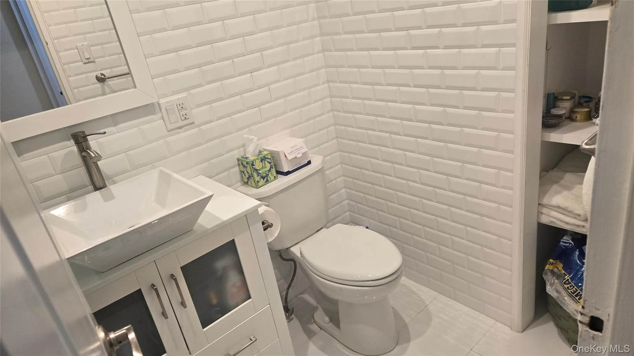 Half bathroom with tile walls, vanity, tile patterned floors, and tasteful backsplash Half bathroom with tile walls, vanity, tile patterned floors, and tasteful backsplash