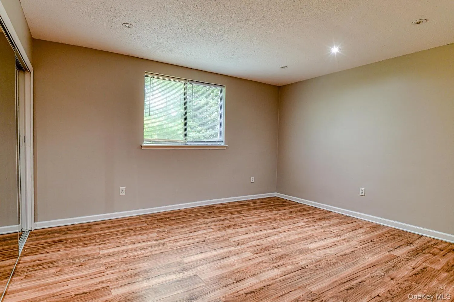 Unfurnished room featuring light wood finished floors, a textured ceiling, and recessed lighting Unfurnished room featuring light wood finished floors, a textured ceiling, and recessed lighting