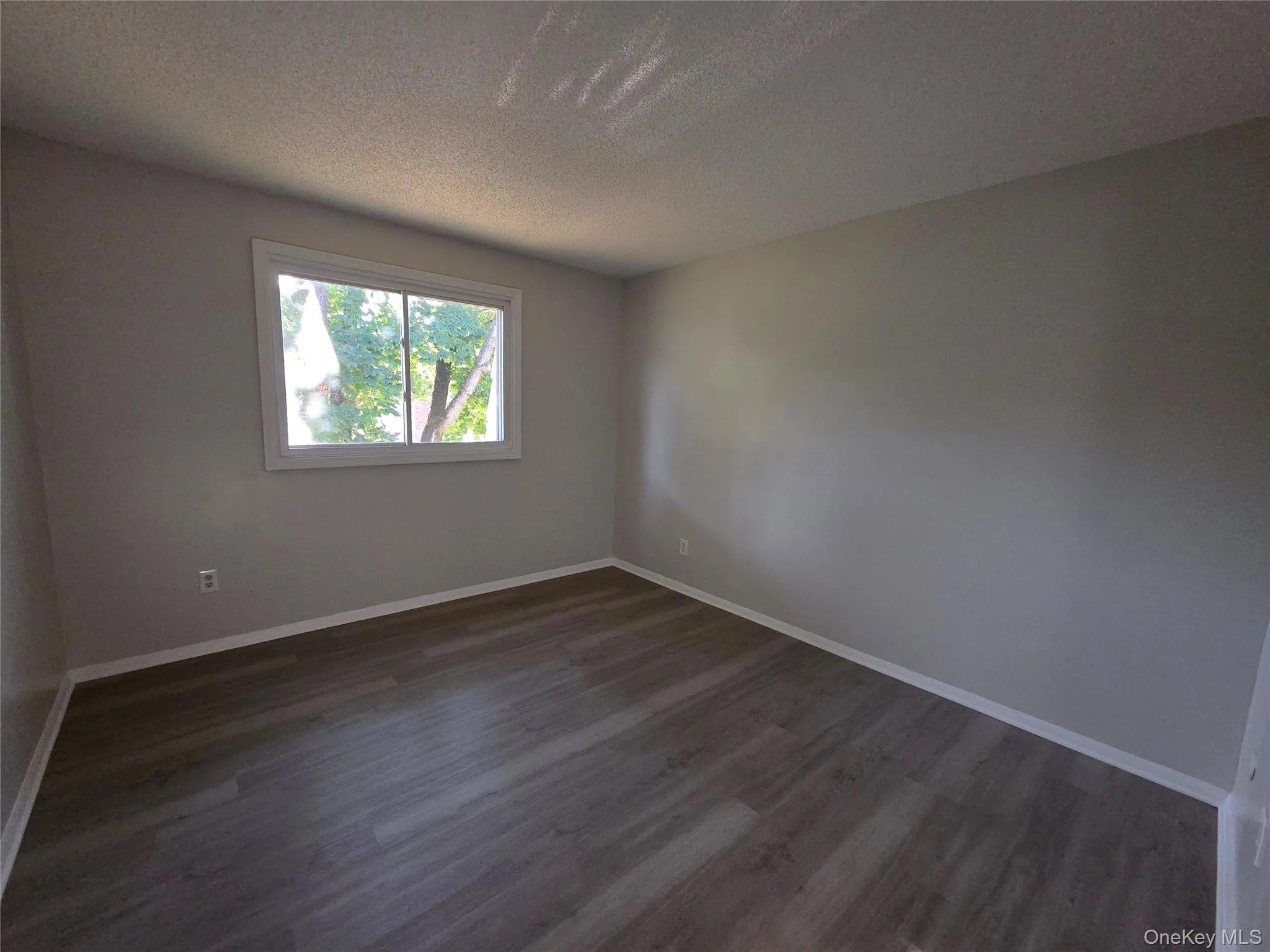 Empty room featuring a textured ceiling and dark wood-type flooring Empty room featuring a textured ceiling and dark wood-type flooring