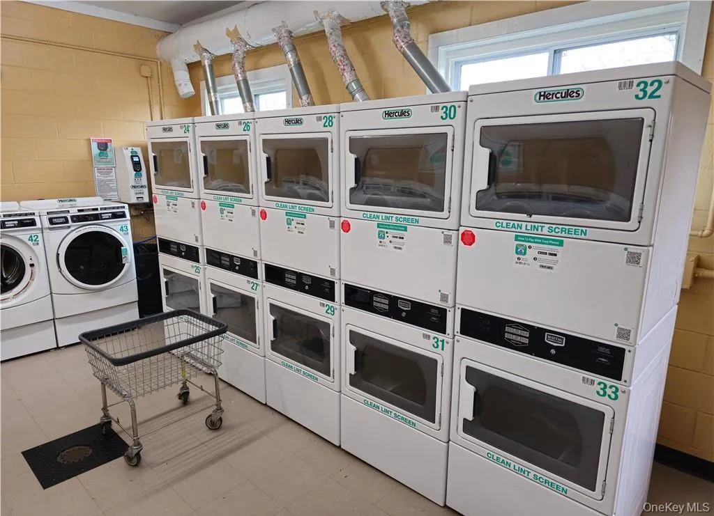Community laundry room with estacked washer and dryer and light flooring Community laundry room with estacked washer and dryer and light flooring