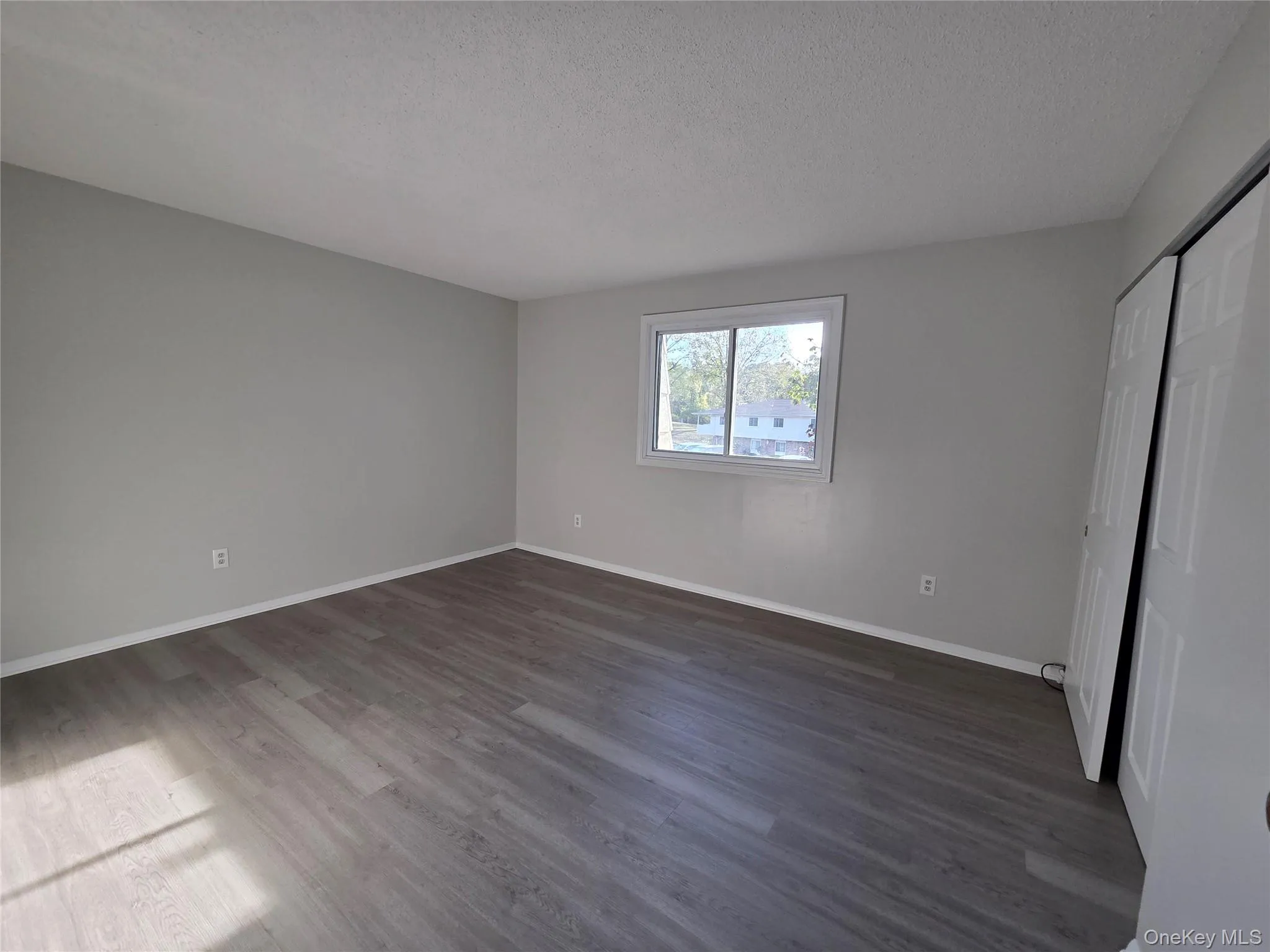 Unfurnished bedroom featuring a closet, dark wood-style floors, and a textured ceiling Unfurnished bedroom featuring a closet, dark wood-style floors, and a textured ceiling