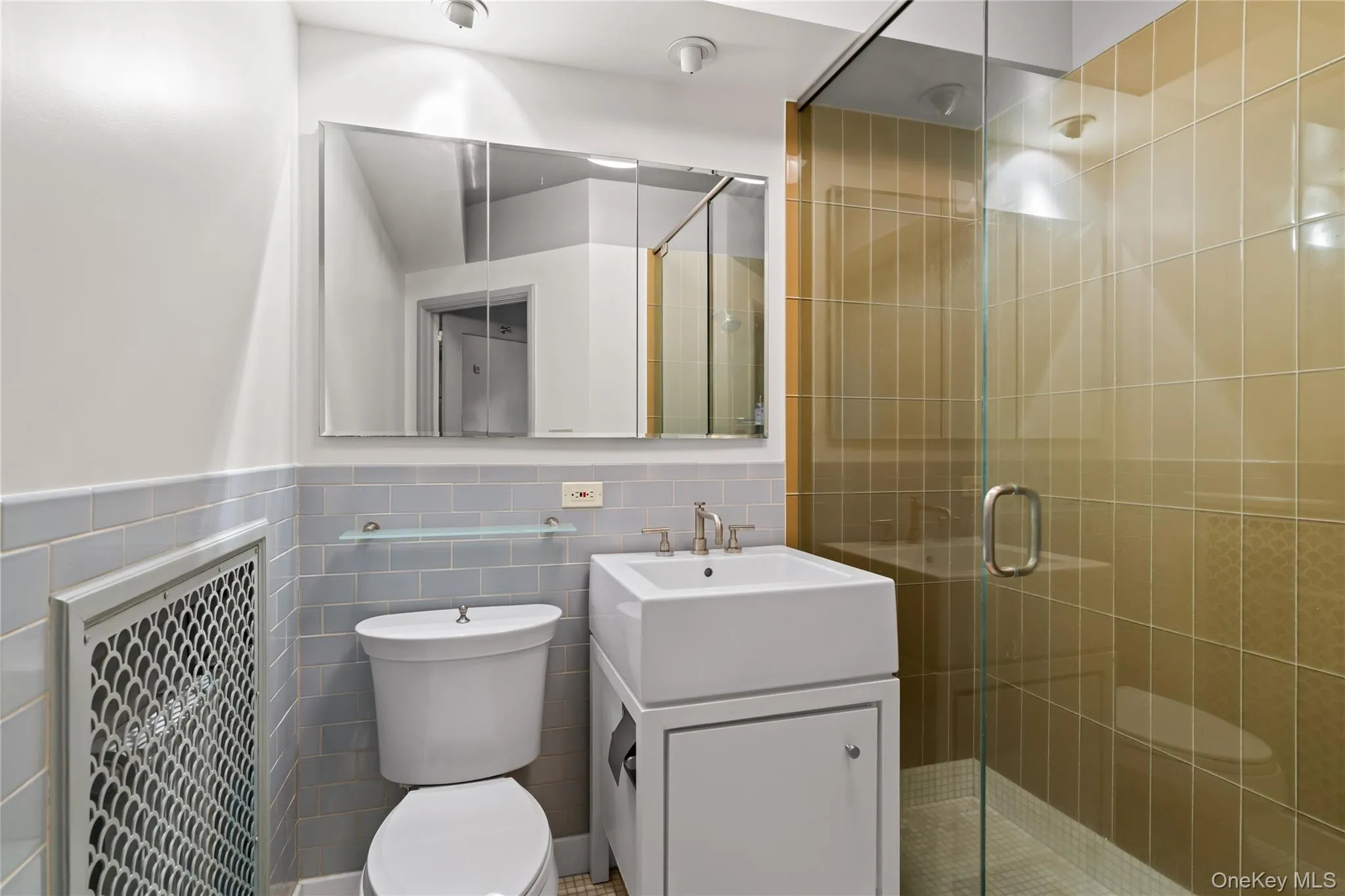 Bathroom with tile walls, a shower stall, vanity, and a wainscoted wall Bathroom with tile walls, a shower stall, vanity, and a wainscoted wall