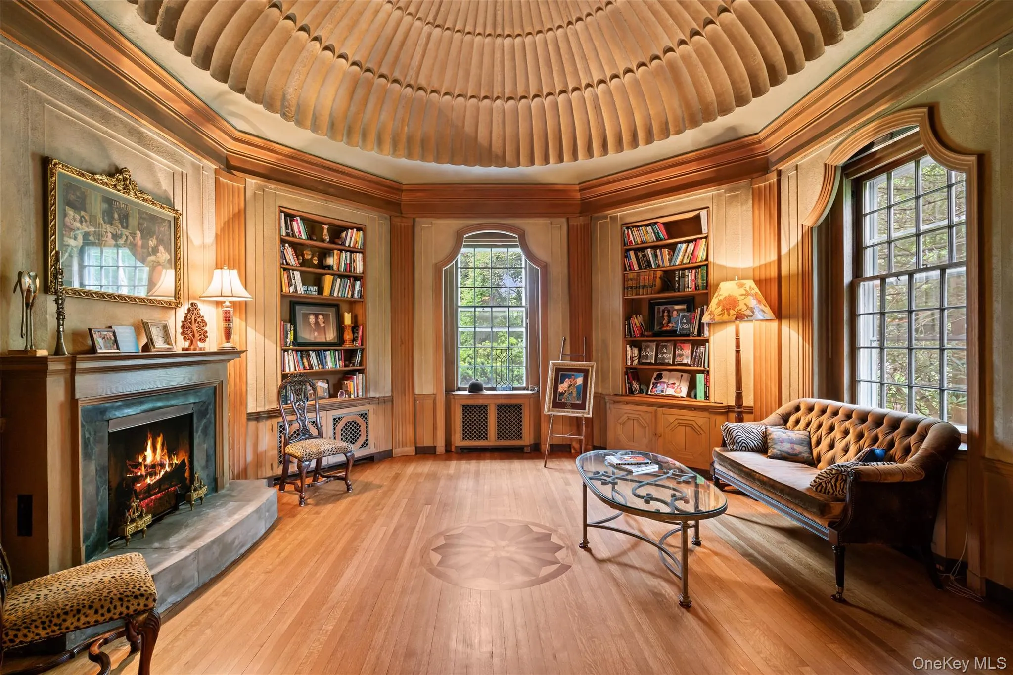 Living area with built in shelves, wood finished floors, a lit fireplace, ornamental molding, and wood walls Living area with built in shelves, wood finished floors, a lit fireplace, ornamental molding, and wood walls
