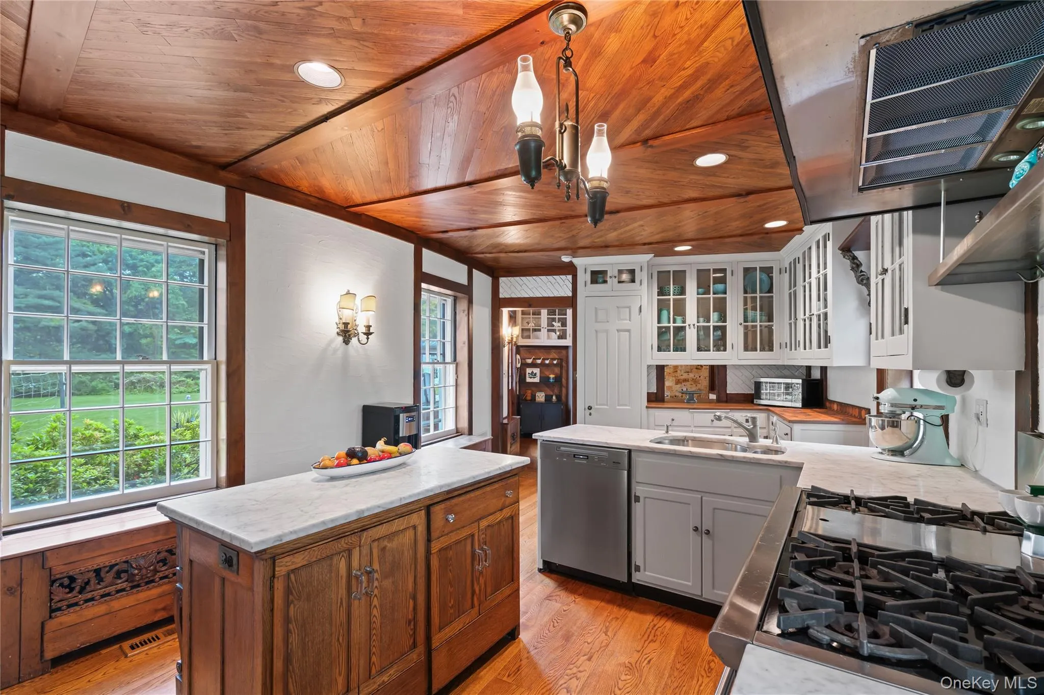 Kitchen with light wood-style floors, exhaust hood, appliances with stainless steel finishes, light countertops, and wood ceiling Kitchen with light wood-style floors, exhaust hood, appliances with stainless steel finishes, light countertops, and wood ceiling