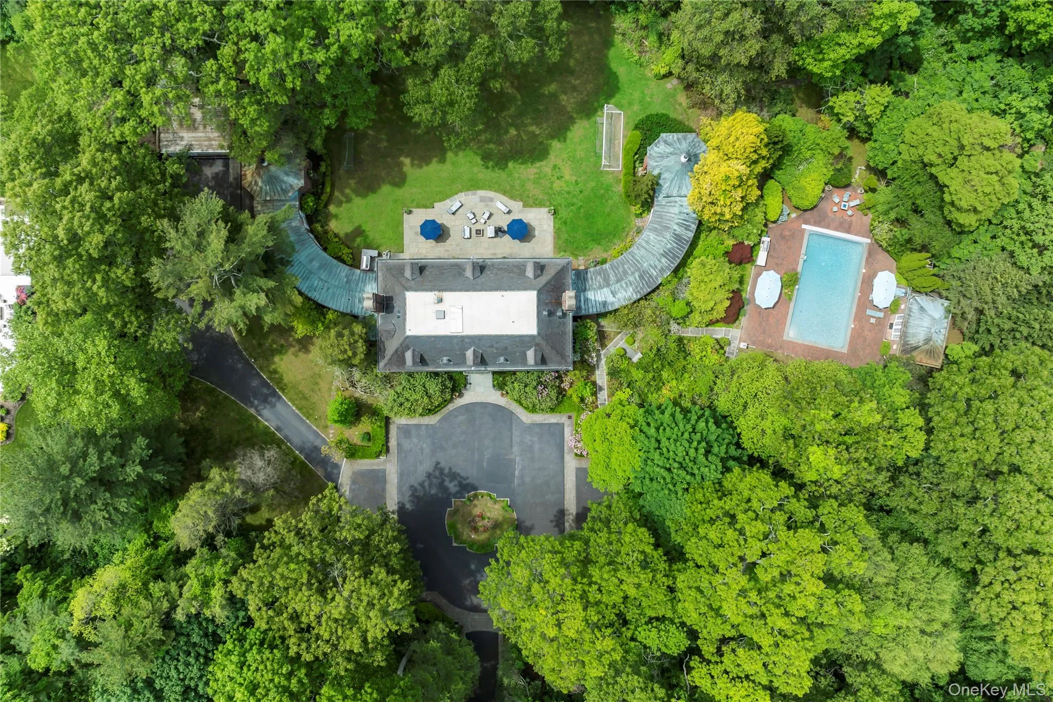 Aerial overview of property's location with a pool and a tree filled landscape Aerial overview of property's location with a pool and a tree filled landscape