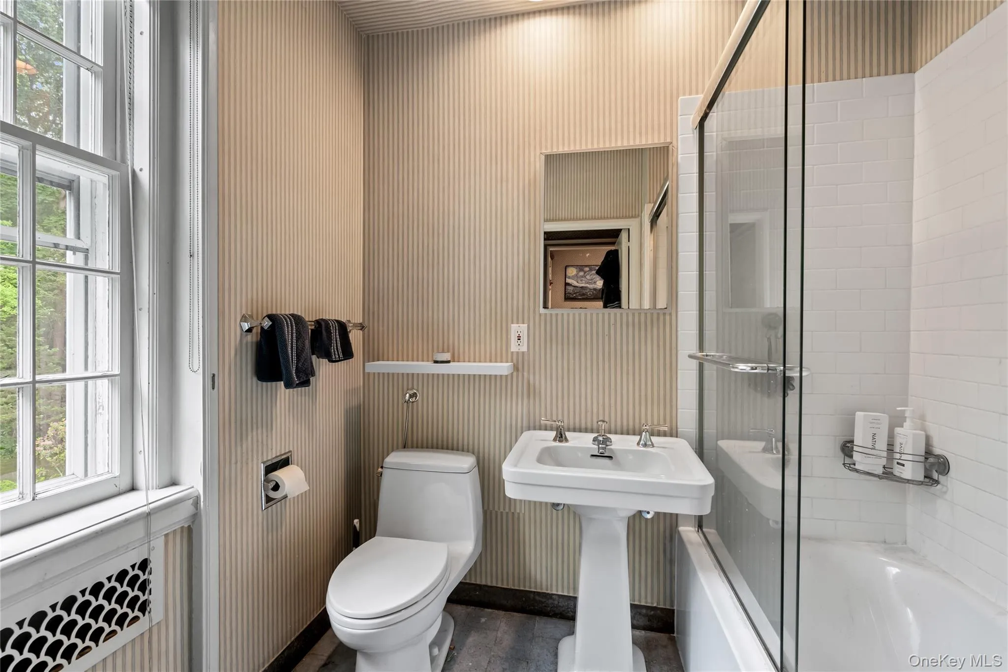Bathroom featuring plenty of natural light, enclosed tub / shower combo, and wallpapered walls Bathroom featuring plenty of natural light, enclosed tub / shower combo, and wallpapered walls