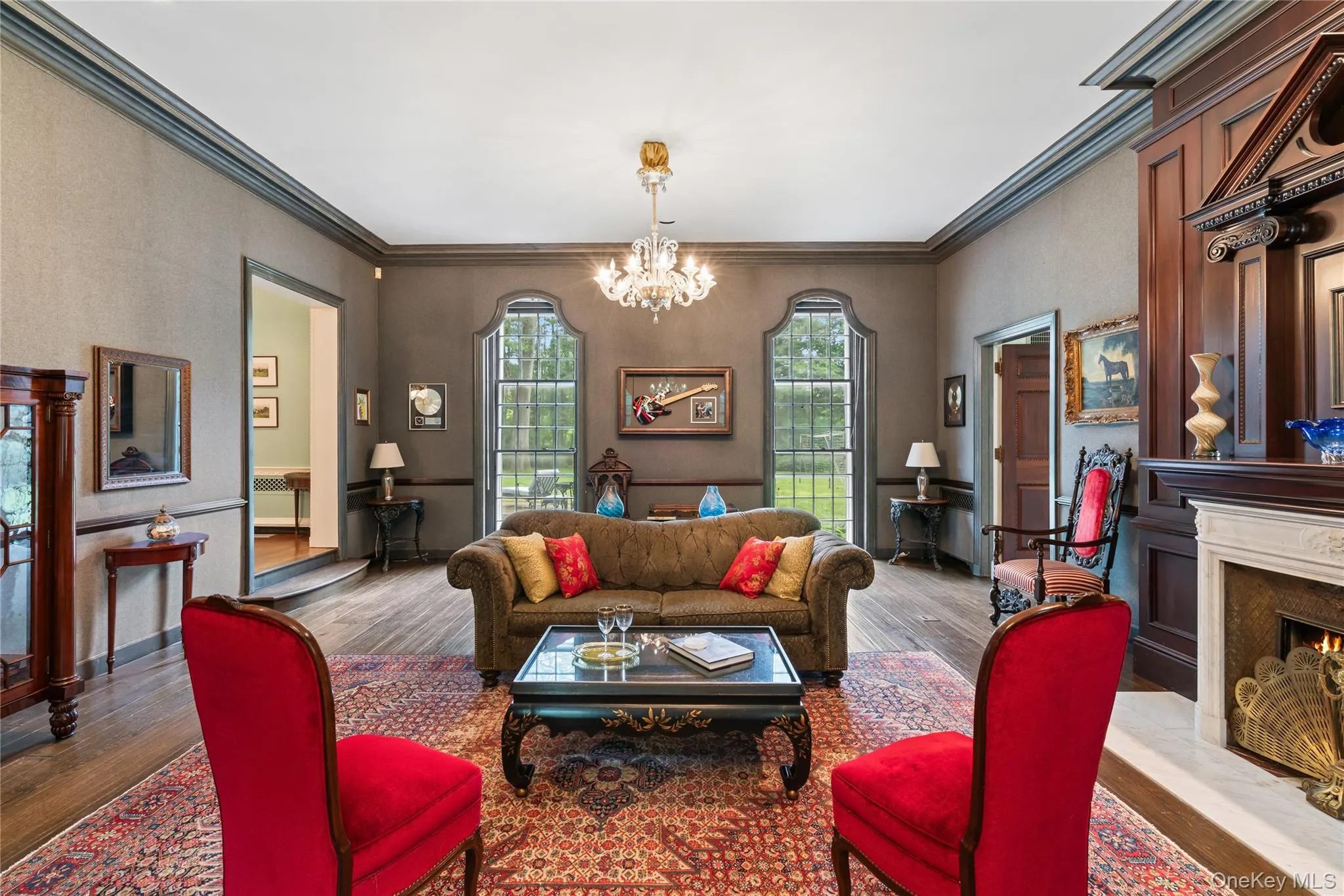 Living room featuring ornamental molding, a high end fireplace, wood finished floors, and a chandelier Living room featuring ornamental molding, a high end fireplace, wood finished floors, and a chandelier