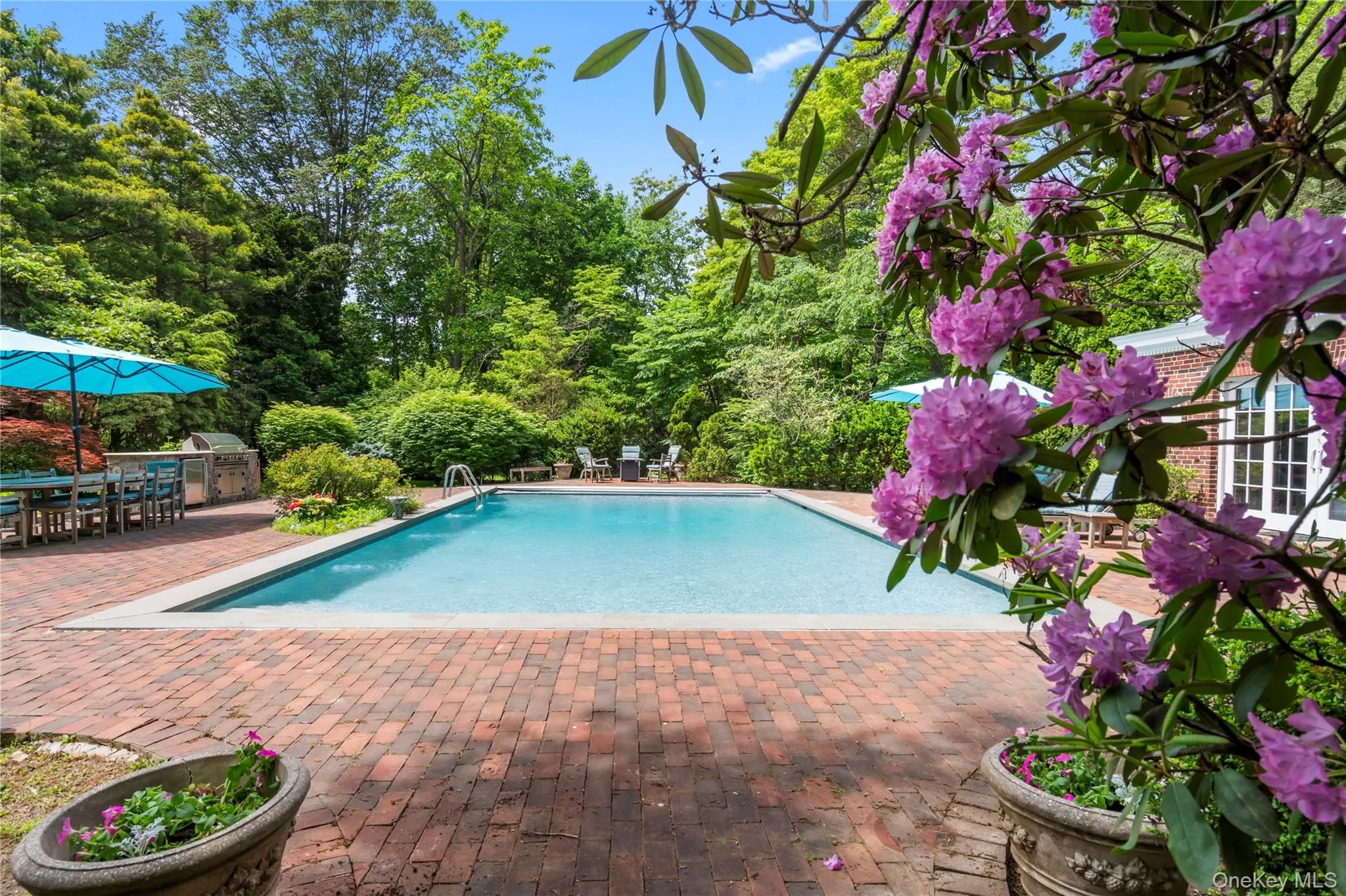 Swimming pool with a patio area, outdoor dining space, and view of wooded area Swimming pool with a patio area, outdoor dining space, and view of wooded area