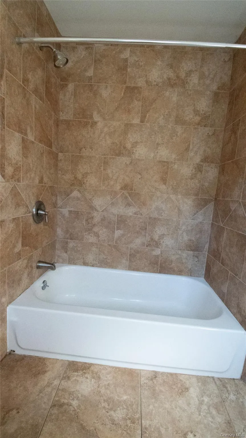 Bathroom featuring shower / bath combination and tile patterned flooring Bathroom featuring shower / bath combination and tile patterned flooring