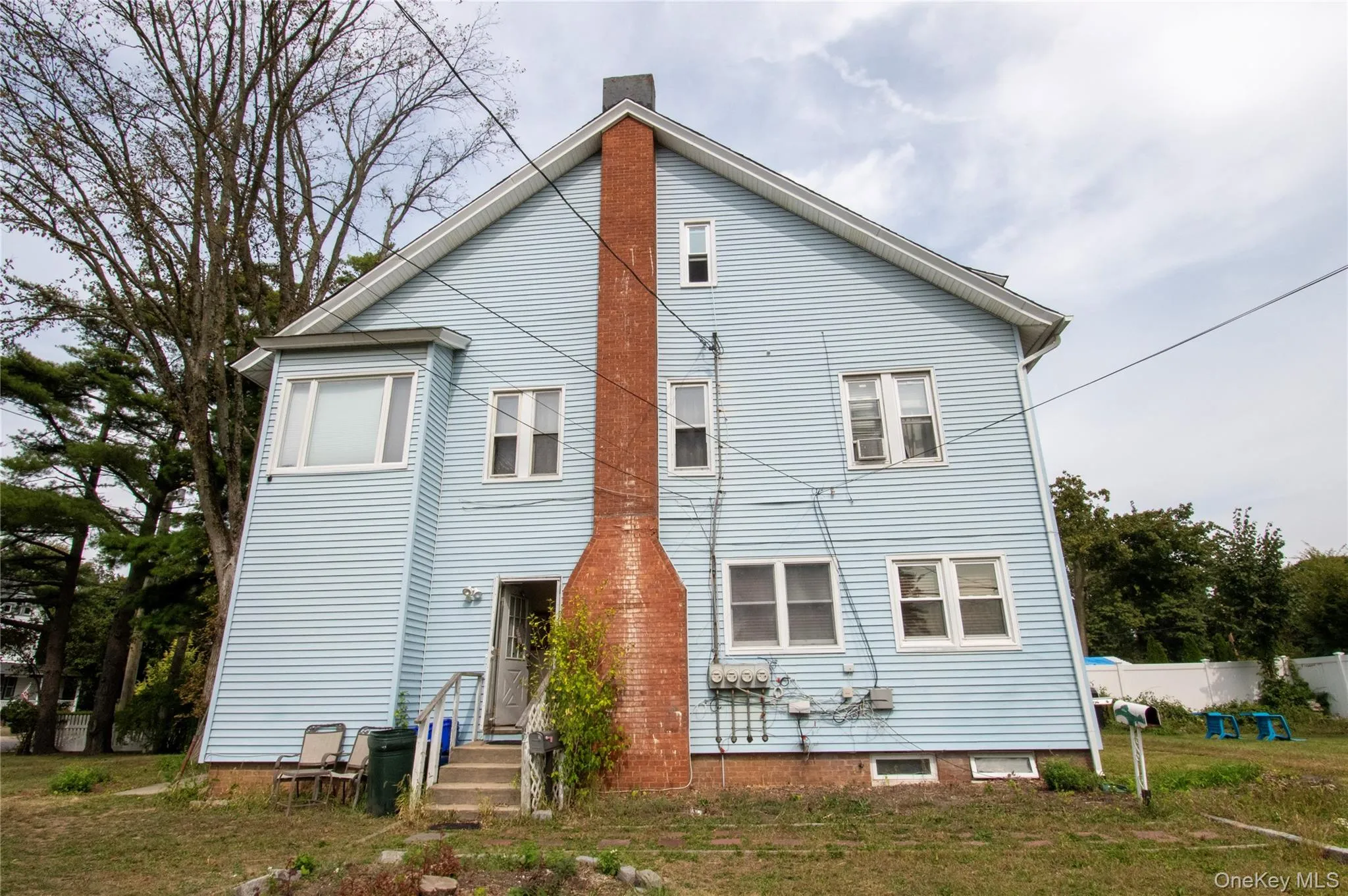 Back of house with a chimney and a lawn Back of house with a chimney and a lawn