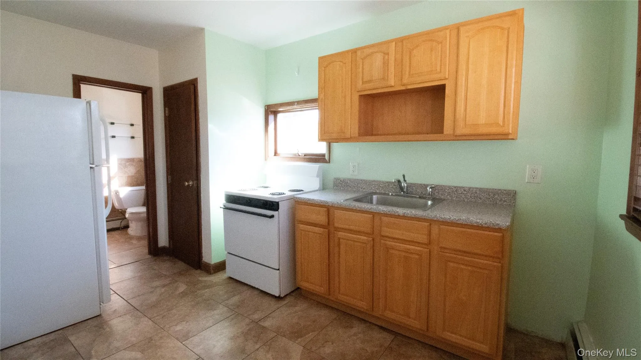 Kitchen with white appliances, light countertops, light brown cabinetry, and light tile patterned flooring Kitchen with white appliances, light countertops, light brown cabinetry, and light tile patterned flooring