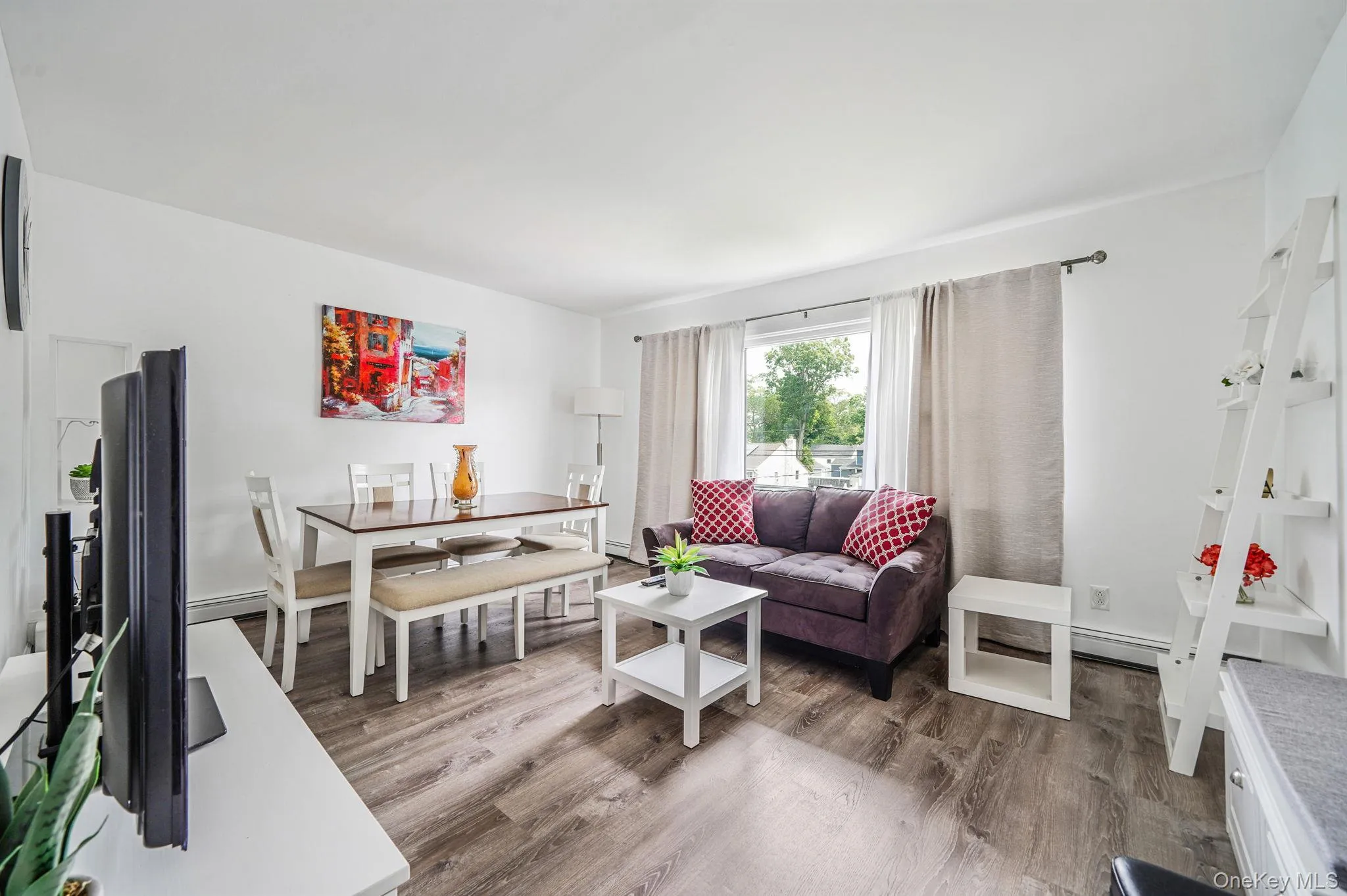 Living area featuring wood finished floors and a baseboard heating unit Living area featuring wood finished floors and a baseboard heating unit